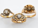 trois bagues en or serties de diamants sur fond blanc