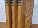 three old books sitting on top of a table next to each other