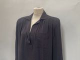 grey shirt on a mannequin stand in front of a white wall