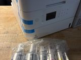 the printer is sitting on the table next to a bunch of batteries