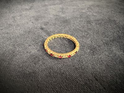 a close up of a gold ring with red stones on a black surface