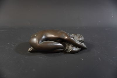 a bronze statue of a woman laying on her stomach