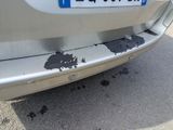 a white car with a blue license plate on it ' s bumper