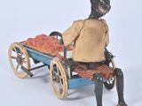 a figurine of a woman sitting on a cart with a basket of fruit