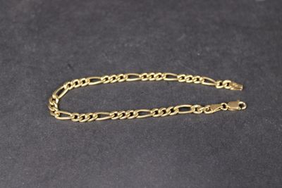 gros plan d'un bracelet en chaîne en or sur une surface noire