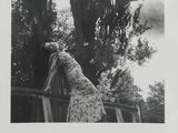 black and white photograph of a woman leaning against a fence