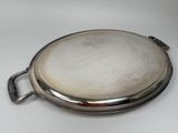 an old silver plate with a handle on a white surface