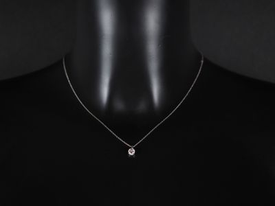 un gros plan sur un mannequin portant un collier orné d'un diamant blanc