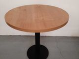 a round wooden table with a black metal base