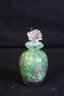 une bouteille en verre verte et jaune avec un bouchon argenté, sur fond noir