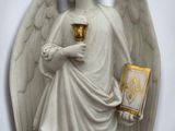 a statue of an angel holding a cup and a book