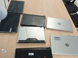 Plusieurs ordinateurs portables sont posés sur une table ronde dans un bureau