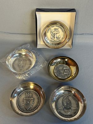 quatre objets en étain dans une boîte, sur lesquels repose une pièce de monnaie