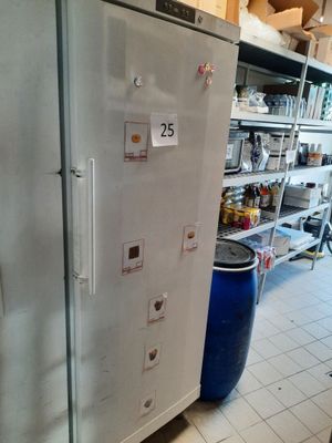un réfrigérateur qui se trouve dans une cuisine, à côté d'une poubelle