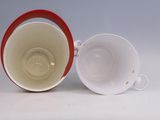 a white and red cup and saucer sitting on a table
