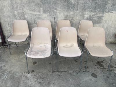 six chaises blanches sont alignées contre un mur en béton