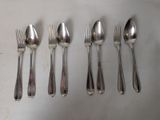 five silver spoons and six silver spoons lined up on a table
