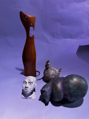 trois sculptures d'animaux et un chat sur fond violet