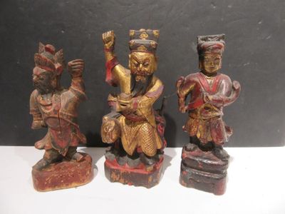 three wooden figurines of asian figures on display on a table