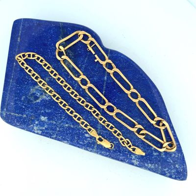 blue stone with gold chains on it on a white surface