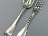 two silver spoons and a fork on a gray surface