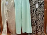 trois paires de pantalons suspendues à un portant dans une pièce