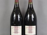two bottles of red wine sitting on top of a glass table