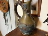 a bronze pitcher sitting on top of a book shelf
