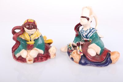 two figurines of a woman and a man sitting on the ground