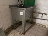 a sink in the corner of a bathroom with a green bucket on it