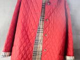 une veste matelassée rouge suspendue à un cintre accroché au mur