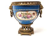 a blue vase with flowers on it sitting on a stand