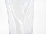 a clear glass vase sitting on a table with a white wall in the background