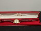une montre Omega dans un coffret rouge posé sur une surface noire