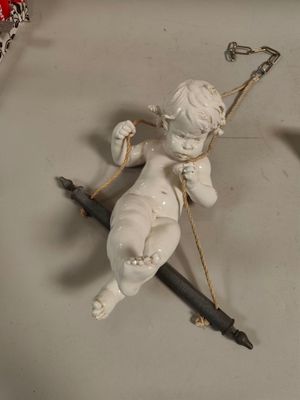 une statue représentant un Cupidon tenant un arc et un stylo, posée sur une table