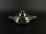 a silver plate with a lid sitting on a black surface