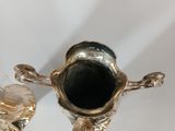 two silver vases sitting on top of a white table