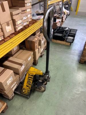 Les cartons sont empilés sur une palette dans un entrepôt à l'aide d'un diable.