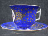 a blue and gold cup and saucer sitting on a table