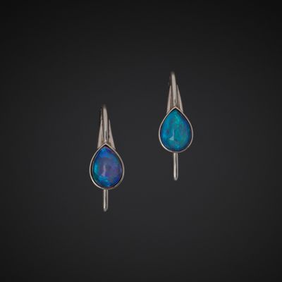 a pair of silver earrings with blue oplite in the shape of a tear