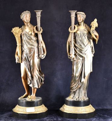 une paire de statues antiques en bronze représentant des femmes tenant des torches