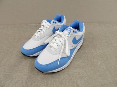 des baskets Nike Air Max blanches et bleues posées sur un canapé
