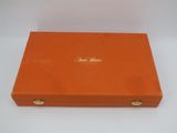 an orange box with gold lettering on it sitting on a white surface