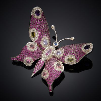 a close up of a pink butterfly broochle on a black surface