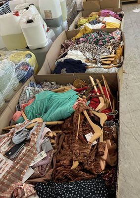 de nombreux cartons contenant des vêtements et d'autres objets, posés par terre