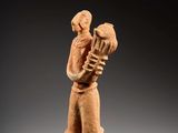 une statue représentant une femme tenant un oiseau, posée sur un socle en bois