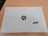 un ordinateur portable HP, sur lequel est collé un autocollant, posé sur une table en bois