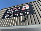 une pancarte apposée sur le côté d'un immeuble sur laquelle on peut lire « Réception Alpha »
