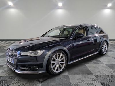 Une Audi noire est garée dans une grande pièce au sol carrelé.