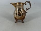 an antique silver plated pitcher sitting on a white surface